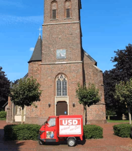 Die USD-Ape vor der Kirche in Loikum – Wahlkampfauftakt der USD Hamminkeln zur Kommunalwahl 2025 im Ortskern von Loikum.